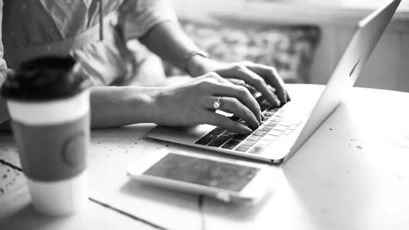 Typing on a laptop beside a coffee cup