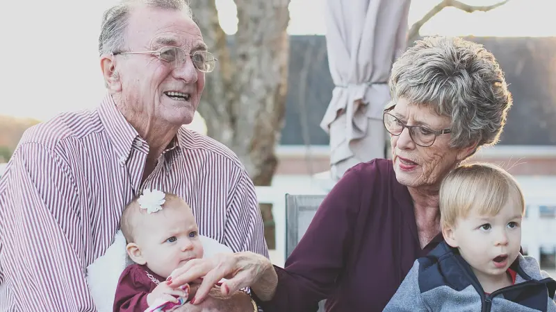 Grandparents sitting outdoors with their two young grandchildren