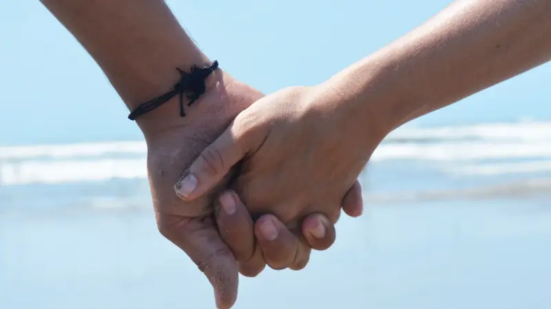 A couple holding hands by the sea