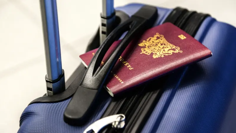 A passport tucked into the handle of a suitcase